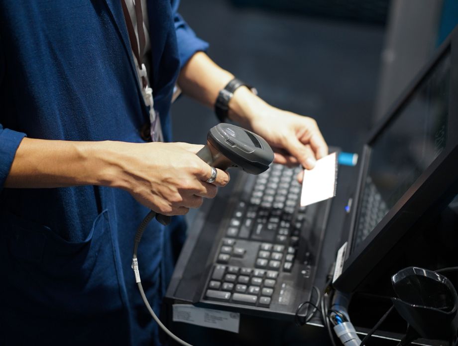 Persona usando un escáner de códigos de barras frente a una computadora.